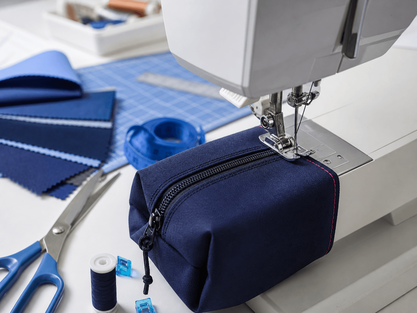 A navy technical pouch at a sewing machine